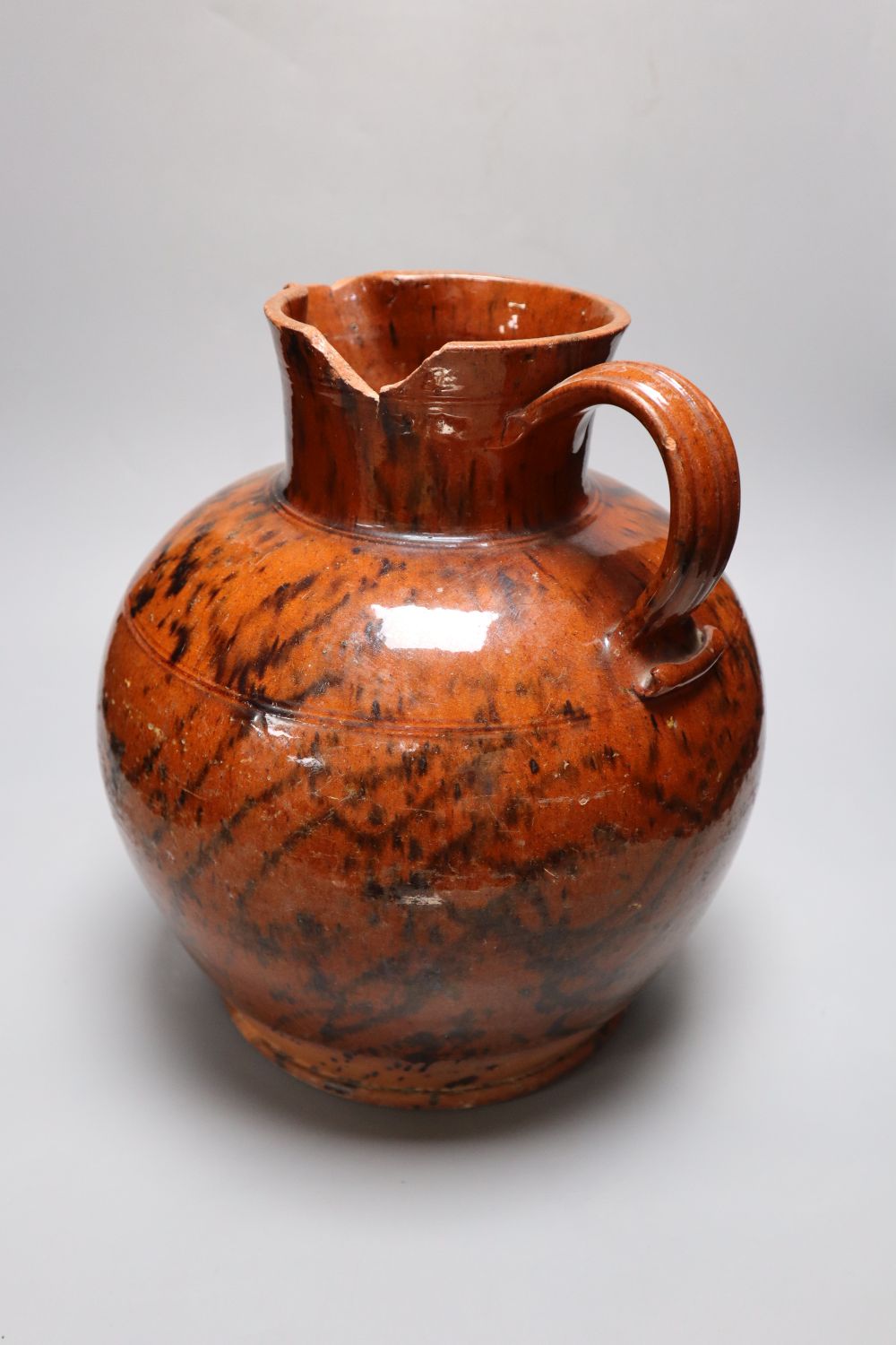 A 19th century Sussex terracotta jug, with black striped glaze, height 30cm (a.f.)